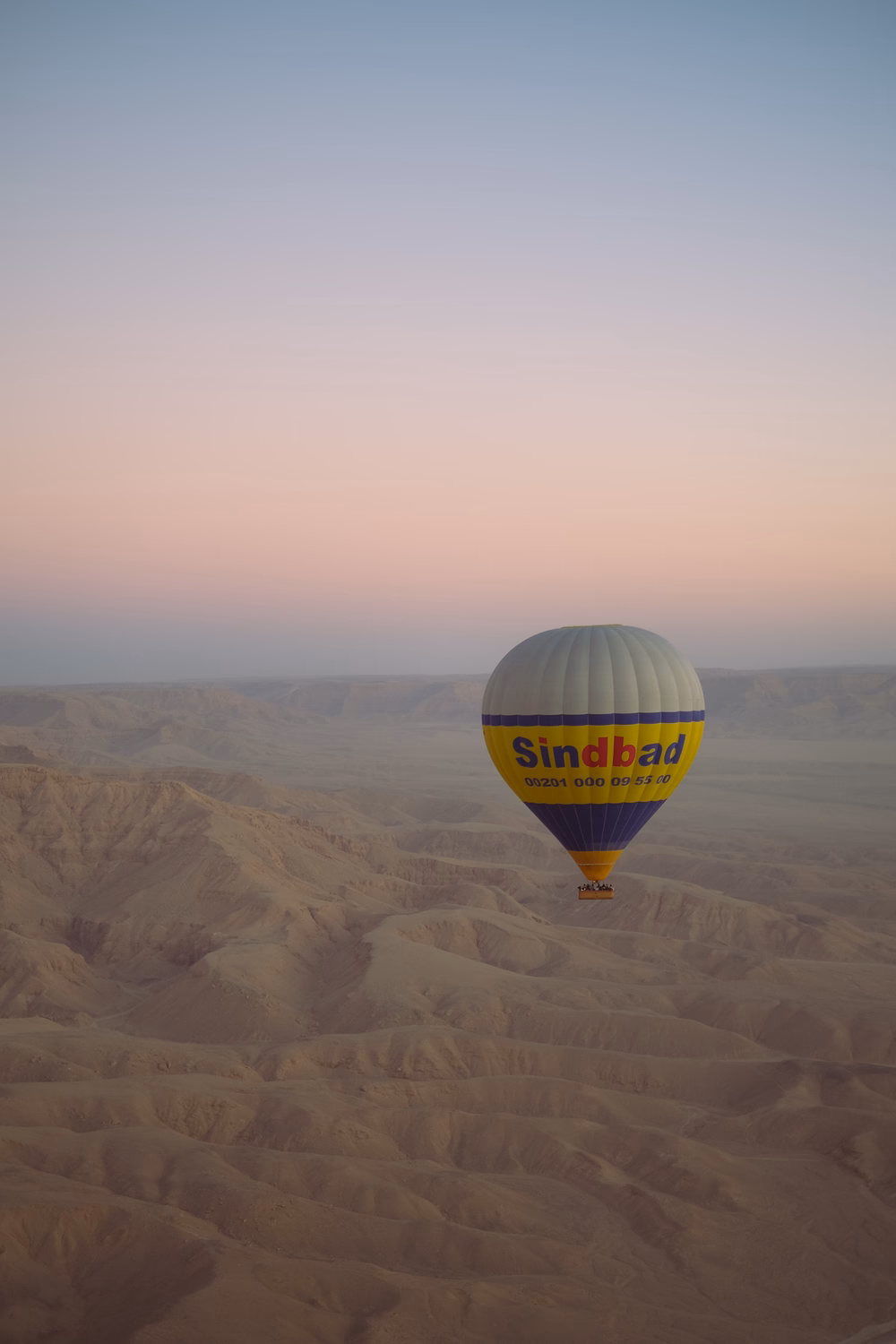 Heißluftballon "Sindbad" schwebt über Wüstenlandschaft bei Sonnenaufgang.