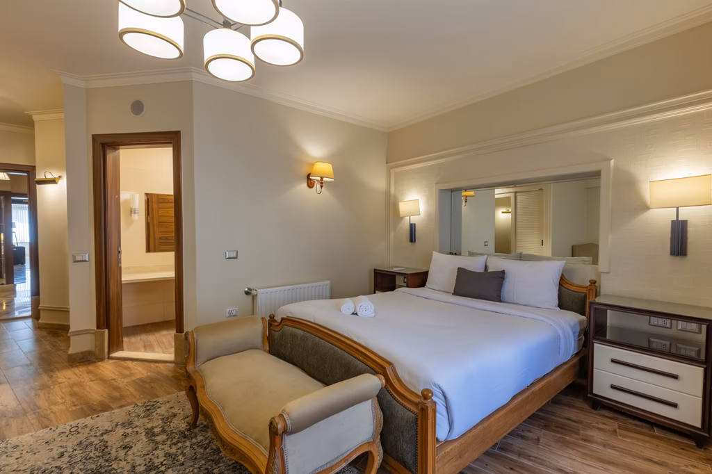 Elegantes Hotelzimmer mit Doppelbett, Sitzbereich und modernem Bad, warmweiße Beleuchtung.