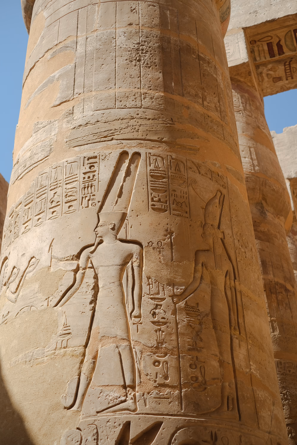 Ägyptische Hieroglyphen und Reliefs auf einer antiken Säule in einem Tempel, zeigend eine Pharaonenfigur.