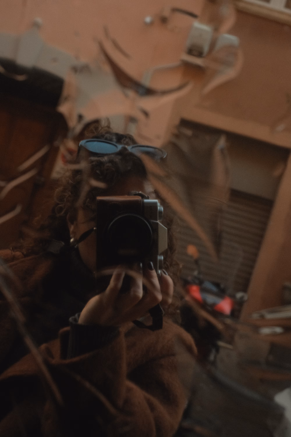 Person mit blauer Brille hält eine Filmkamera in den Händen und fotografiert selbst.